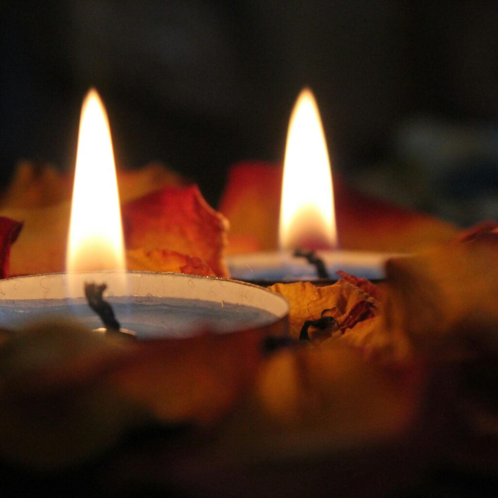 Close-up of candles with flames surrounded by rose petals, creating a warm ambiance.