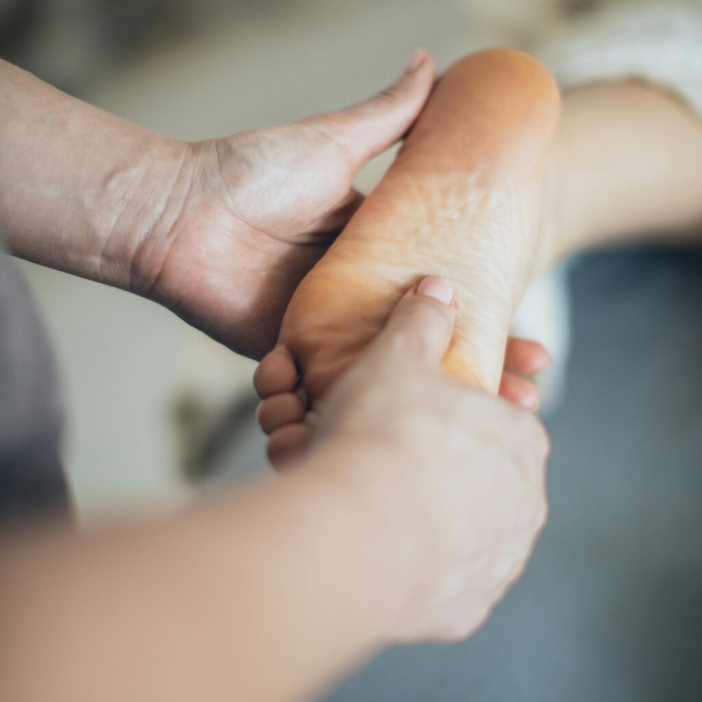 Close-up of hands giving a relaxing foot massage in a spa setting, promoting wellness.