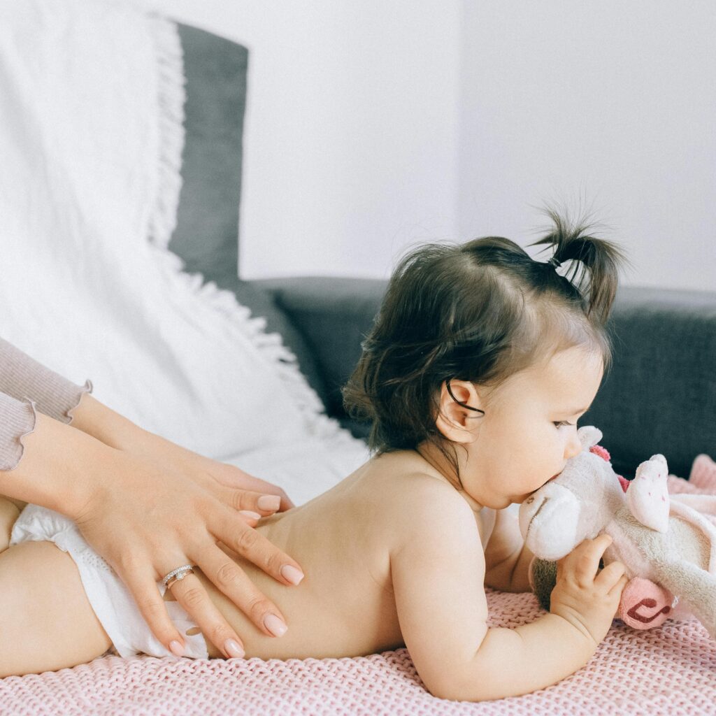 A serene moment of a baby receiving a gentle massage while holding a plush toy, epitomizing peace and comfort.