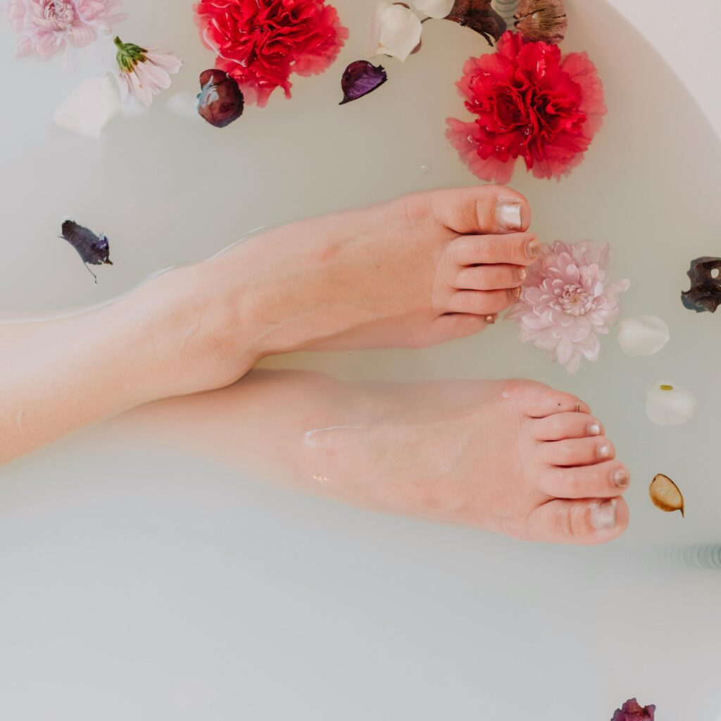 A serene image of feet soaking in a floral bath surrounded by vibrant flowers and petals.