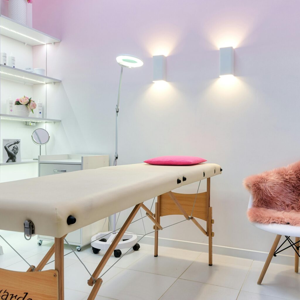 Interior of contemporary workplace of cosmetology salon with couch placed near armchair and shelves with cosmetic products